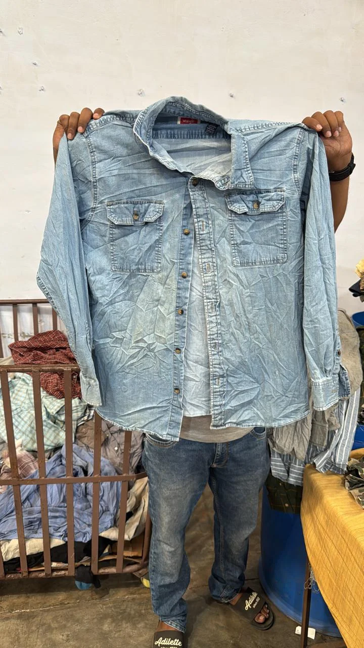 A light denim shirt held up to show its front and details